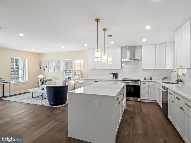 kitchen featuring dark wood-style flooring, a sink, open floor plan, wall chimney range hood, and appliances with stainless steel finishes