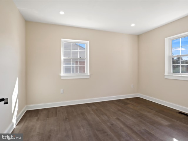 spare room featuring dark wood-type flooring, visible vents, and baseboards