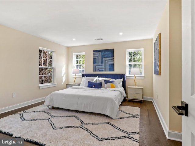 bedroom with dark wood-style floors, baseboards, multiple windows, and visible vents