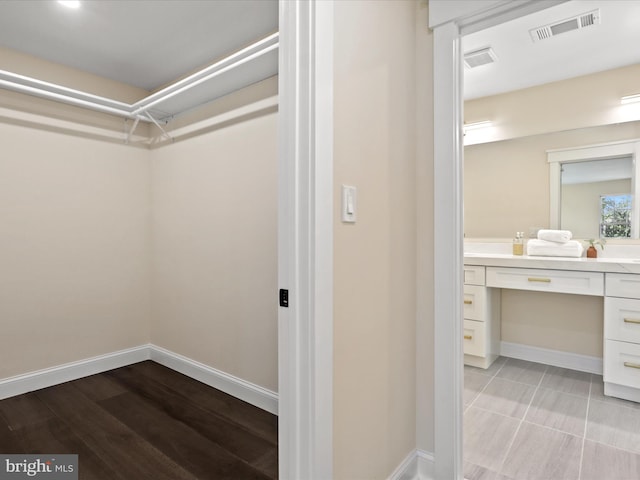 spacious closet with light wood-type flooring, visible vents, and built in study area