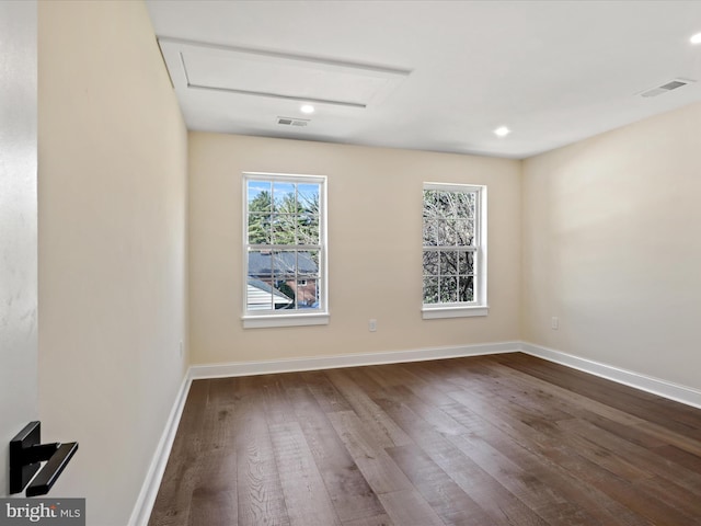 spare room featuring visible vents, baseboards, and dark wood-type flooring