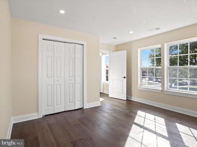 unfurnished bedroom with baseboards, visible vents, and dark wood-style flooring