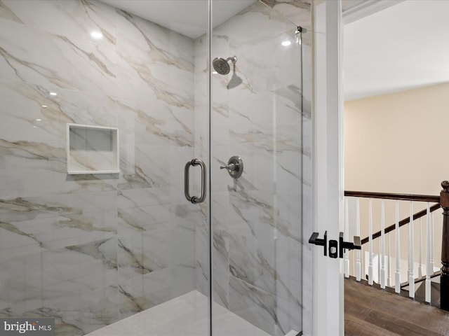 full bath with a marble finish shower and wood finished floors