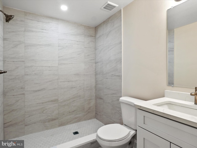 full bath featuring visible vents, a tile shower, vanity, and toilet