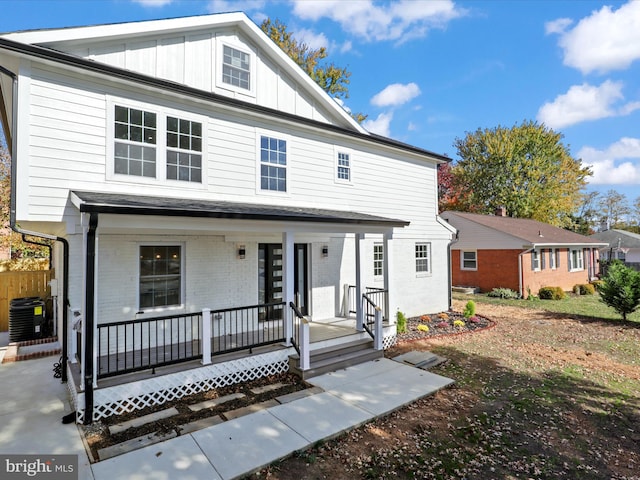 view of front of house featuring covered porch, central AC unit, board and batten siding, and brick siding