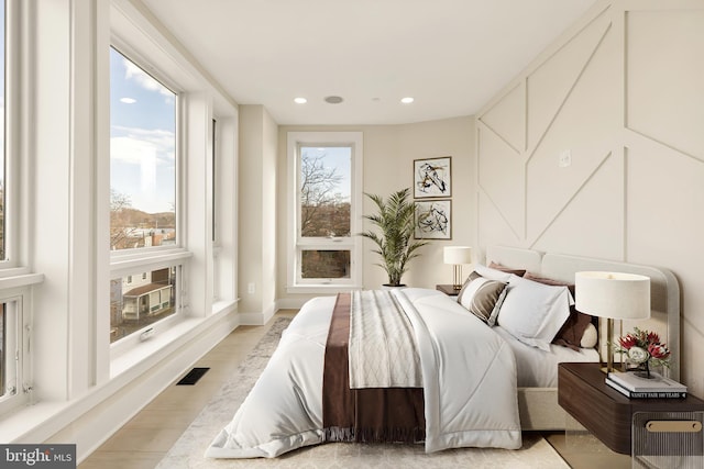 bedroom featuring recessed lighting, visible vents, light wood-style flooring, and multiple windows