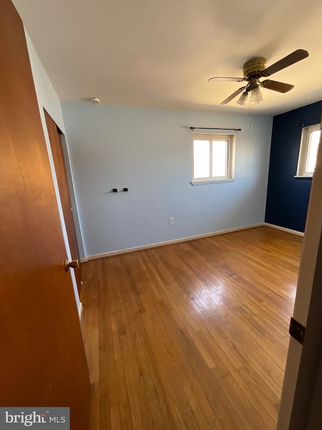 spare room with a ceiling fan, baseboards, and wood-type flooring