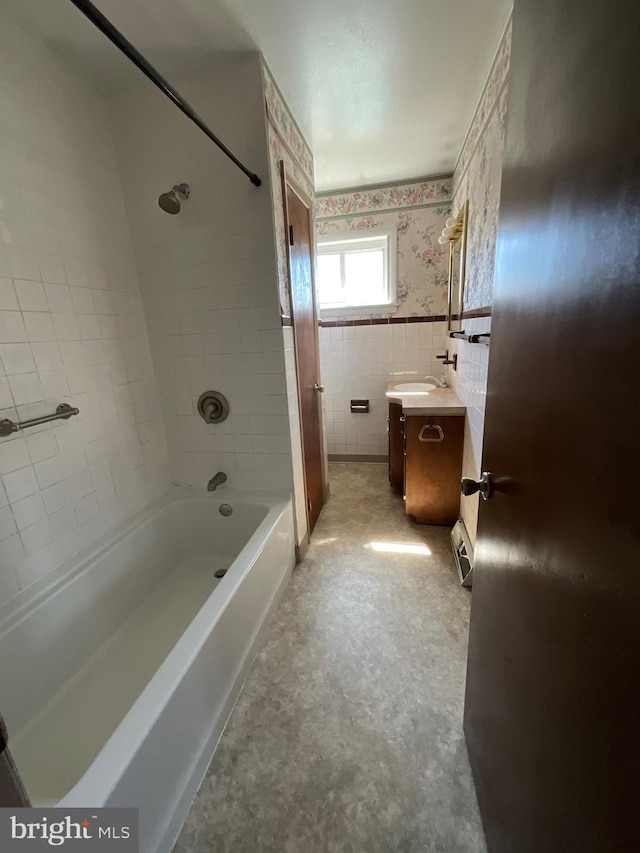 full bath with vanity, wallpapered walls, wainscoting, shower / bath combination, and tile walls