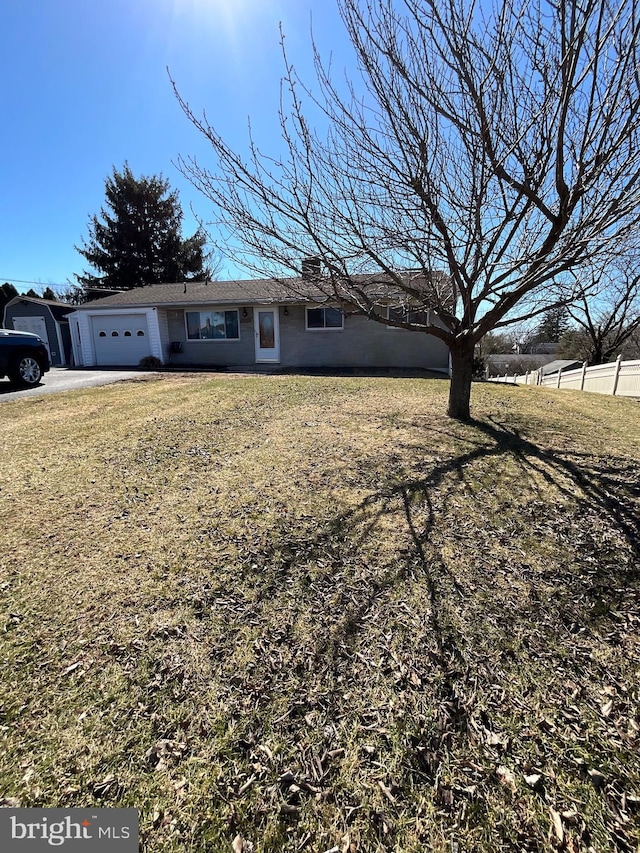 view of front of property with a front yard, an attached garage, and fence