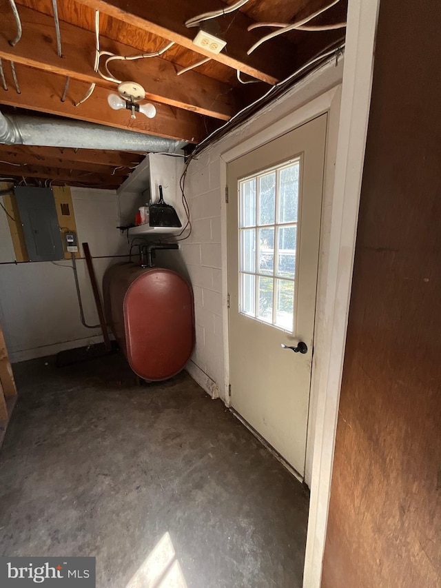 interior space featuring electric panel, concrete block wall, and heating fuel