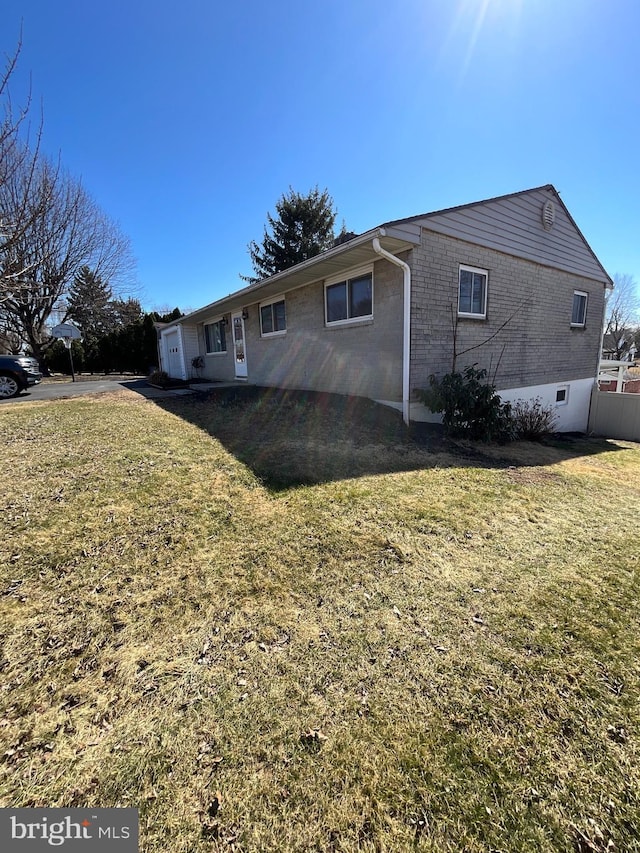 rear view of house featuring brick siding and a lawn