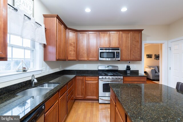 kitchen featuring stainless steel appliances, recessed lighting, light wood-style floors, brown cabinetry, and a sink