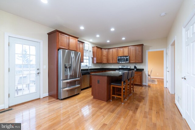 kitchen featuring a breakfast bar, a kitchen island, visible vents, appliances with stainless steel finishes, and dark countertops