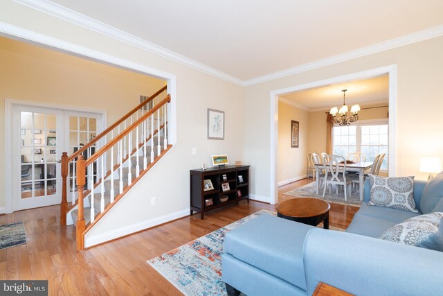 living area featuring stairway, ornamental molding, wood finished floors, a chandelier, and baseboards