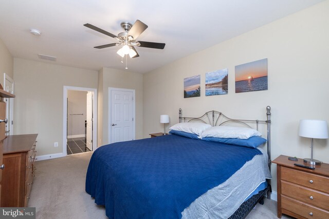 bedroom with light carpet, ceiling fan, baseboards, and ensuite bathroom