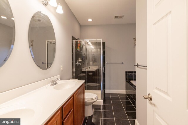 bathroom with double vanity, toilet, a stall shower, a sink, and tile patterned floors