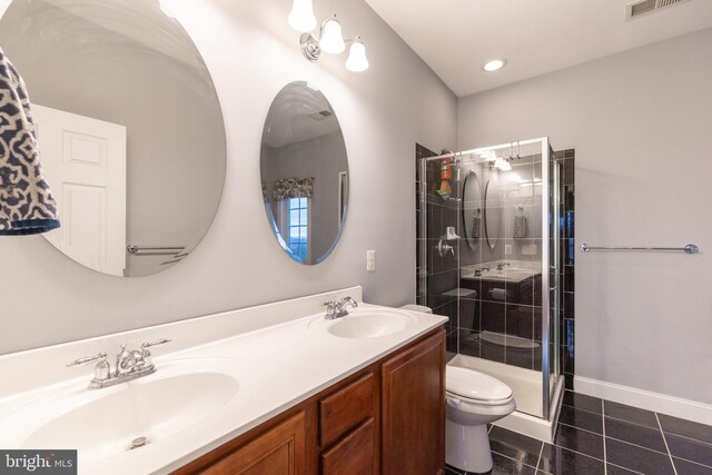 bathroom featuring tile patterned flooring, a sink, toilet, and a shower stall