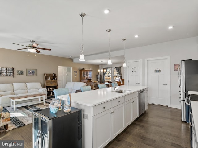 kitchen featuring a center island with sink, a sink, open floor plan, dark wood finished floors, and appliances with stainless steel finishes