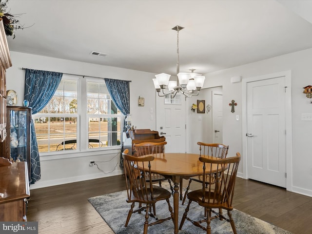 dining area featuring a notable chandelier, visible vents, baseboards, and wood finished floors