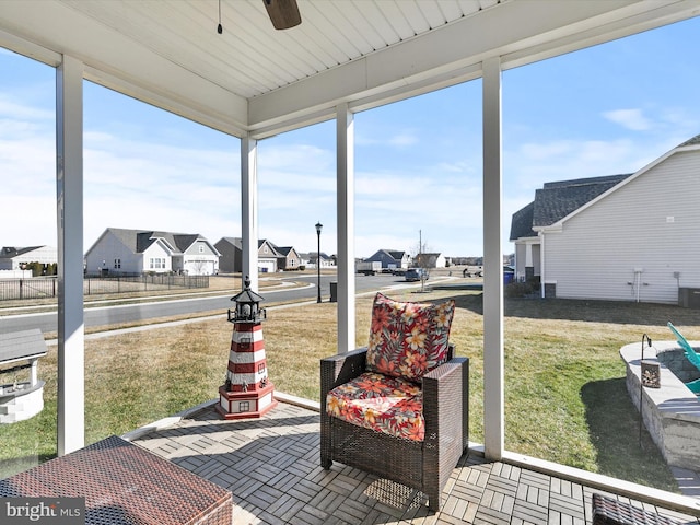 sunroom / solarium featuring a ceiling fan and a residential view