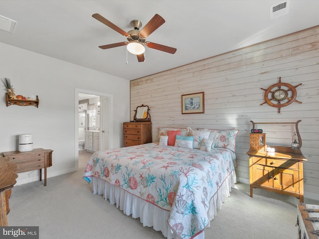 bedroom featuring a ceiling fan, light colored carpet, visible vents, and connected bathroom