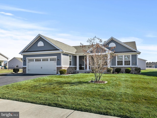 craftsman-style house with aphalt driveway, stone siding, an attached garage, and a front yard