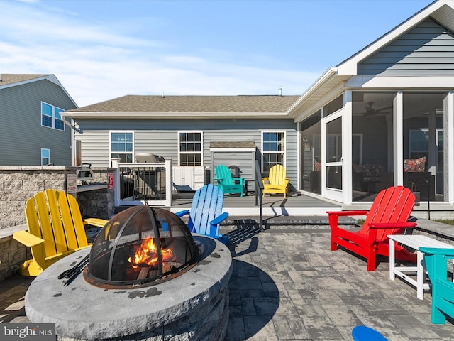 view of patio / terrace featuring a grill, a sunroom, and an outdoor fire pit