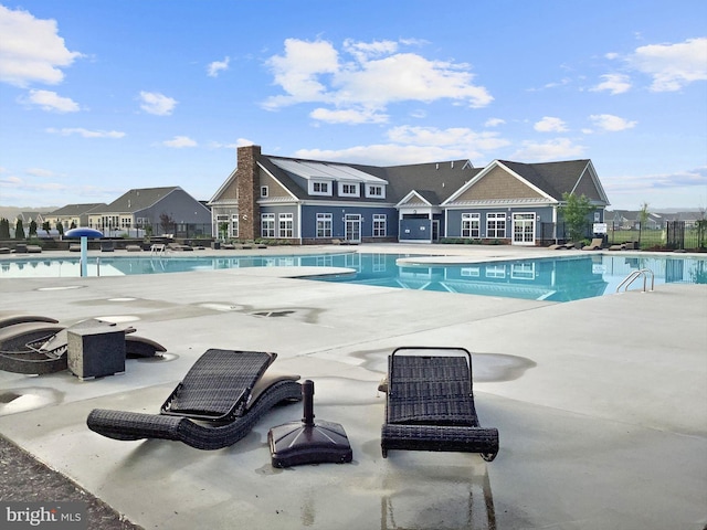 community pool with a patio area and fence