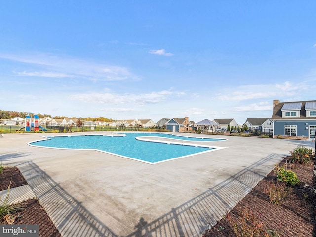 community pool featuring a patio, fence, and a residential view