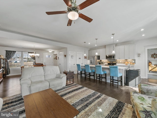 living area with recessed lighting, baseboards, dark wood-style flooring, and ceiling fan with notable chandelier