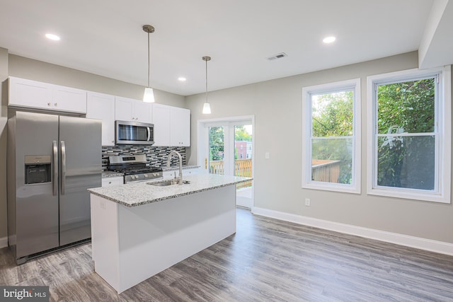 kitchen featuring stainless steel appliances, visible vents, decorative backsplash, a kitchen island with sink, and a sink