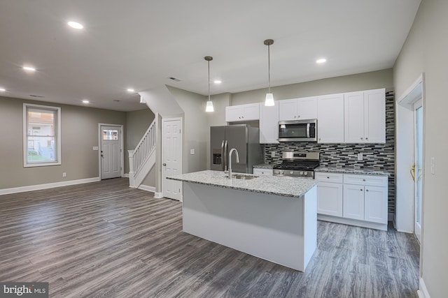 kitchen with a sink, stainless steel appliances, wood finished floors, and an island with sink