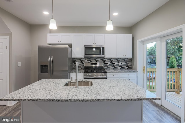 kitchen featuring a sink, wood finished floors, white cabinets, appliances with stainless steel finishes, and backsplash