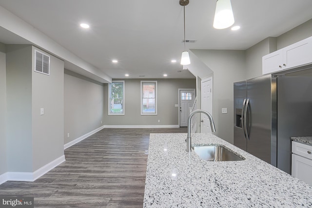 kitchen with dark wood-style flooring, a sink, visible vents, white cabinetry, and stainless steel fridge