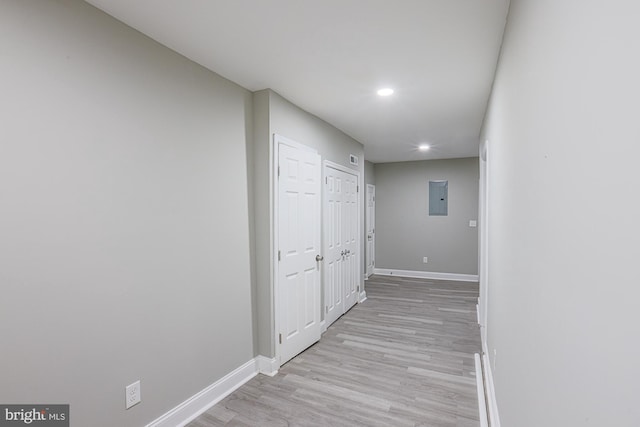 hall featuring recessed lighting, electric panel, light wood finished floors, and baseboards