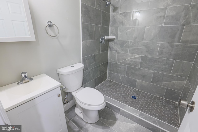 bathroom featuring tiled shower, vanity, and toilet