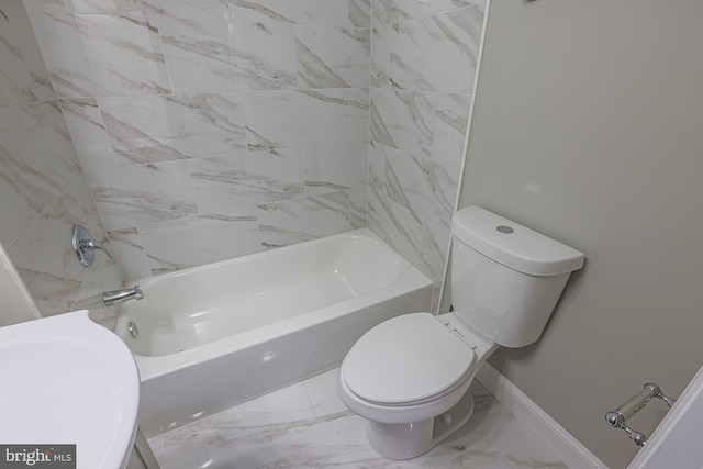 bathroom featuring marble finish floor, baseboards, shower / bathing tub combination, and toilet