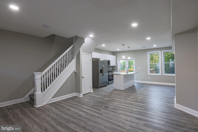 kitchen featuring dark wood-style floors, stainless steel appliances, an island with sink, and white cabinets