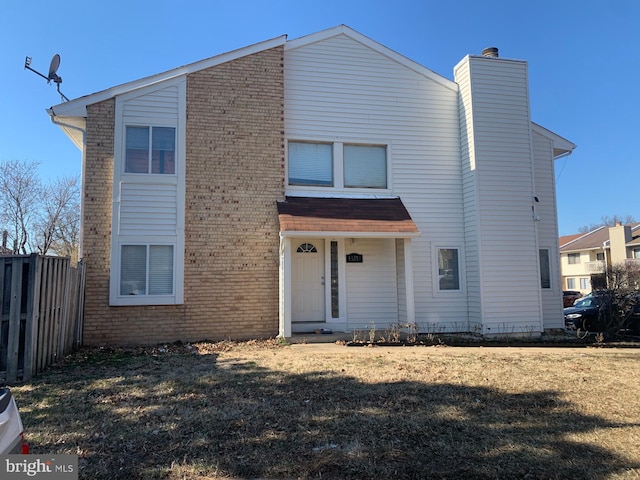 view of front facade with a chimney, a front yard, fence, and brick siding