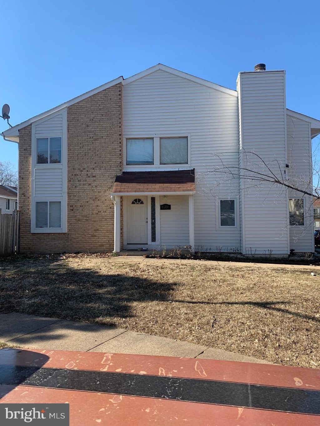 view of front facade featuring a chimney, a front lawn, and brick siding