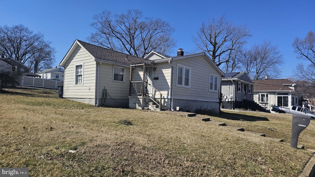 view of front of house with a chimney, fence, and a front yard