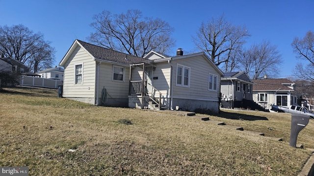 view of front of house with a chimney, fence, and a front yard