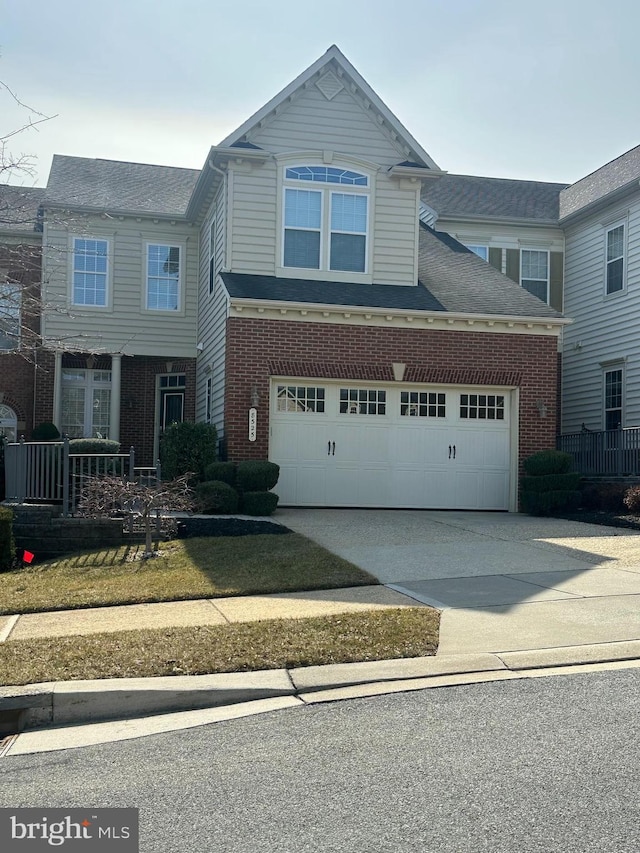 traditional home with a garage, concrete driveway, and brick siding