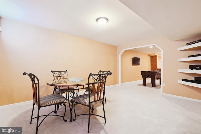 dining space featuring arched walkways, light colored carpet, and baseboards