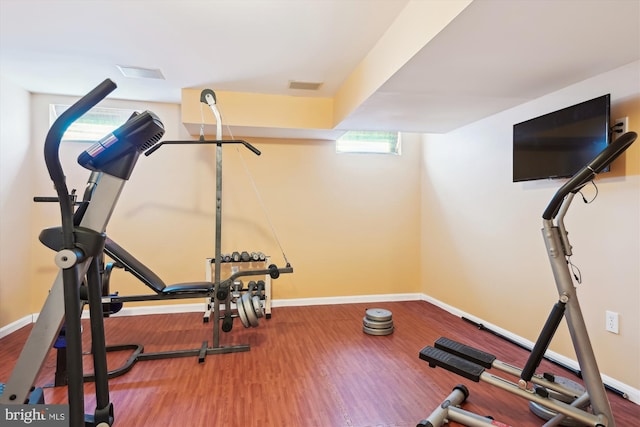 exercise area with visible vents, baseboards, and wood finished floors