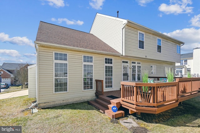 back of property featuring a yard, a wooden deck, and roof with shingles