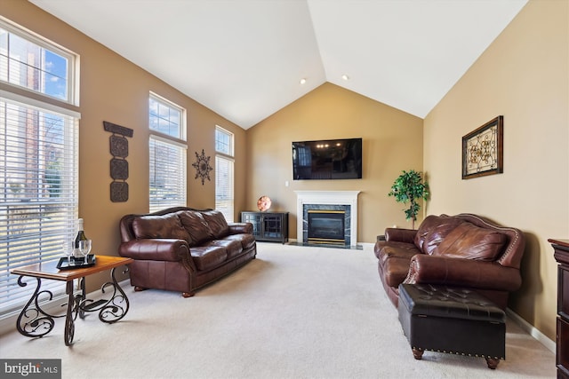 carpeted living room featuring plenty of natural light, baseboards, a high end fireplace, and high vaulted ceiling