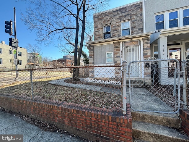 view of front facade with stone siding, a fenced front yard, and a gate