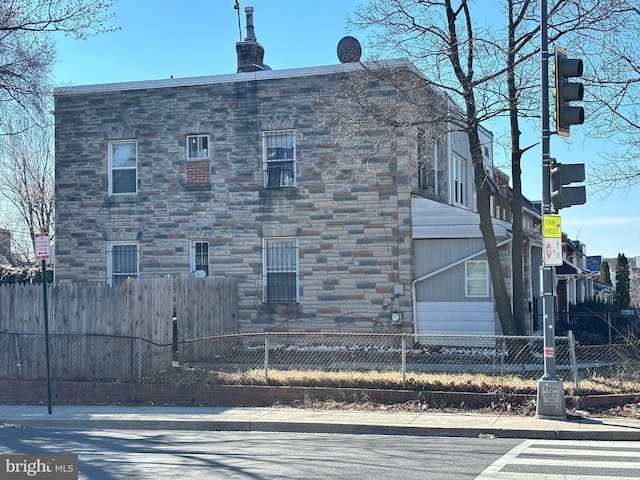 view of home's exterior with stone siding and a fenced front yard