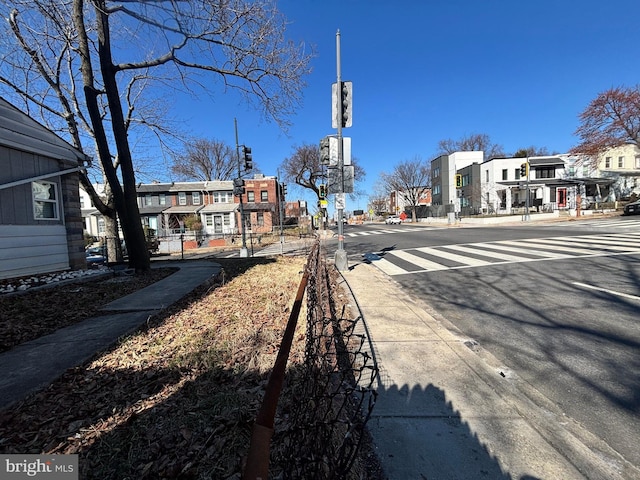 view of road featuring curbs, traffic lights, sidewalks, and a residential view